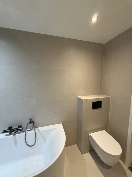 Wandtoilet en ligbad in de afgewerkte badkamer