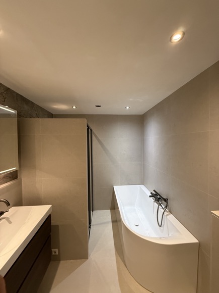 Overzicht van de badkamer met bad, wastafel en douche